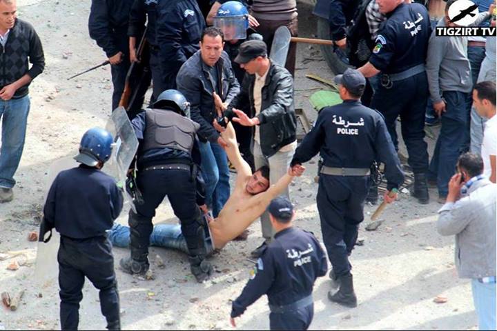 Photo A : Policiers algériens se conduisant comme des sauvages sur le corps d'un Kabyle (PH/Tigzirt TV)